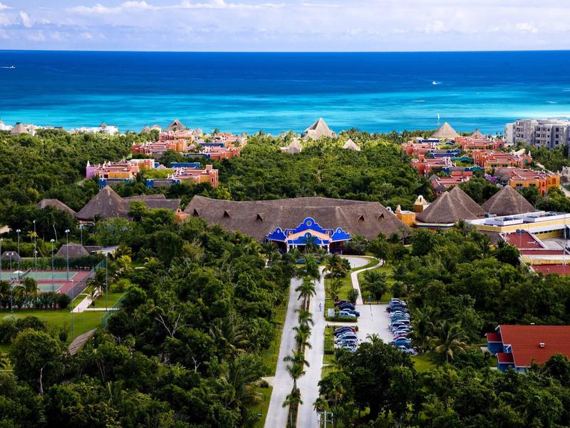 Resort con vegetazione rigogliosa vicino a un oceano blu sotto un cielo sereno.