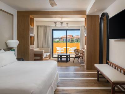 Camera d'hotel moderna con letto grande, TV a schermo piatto e balcone con vista sulla città.