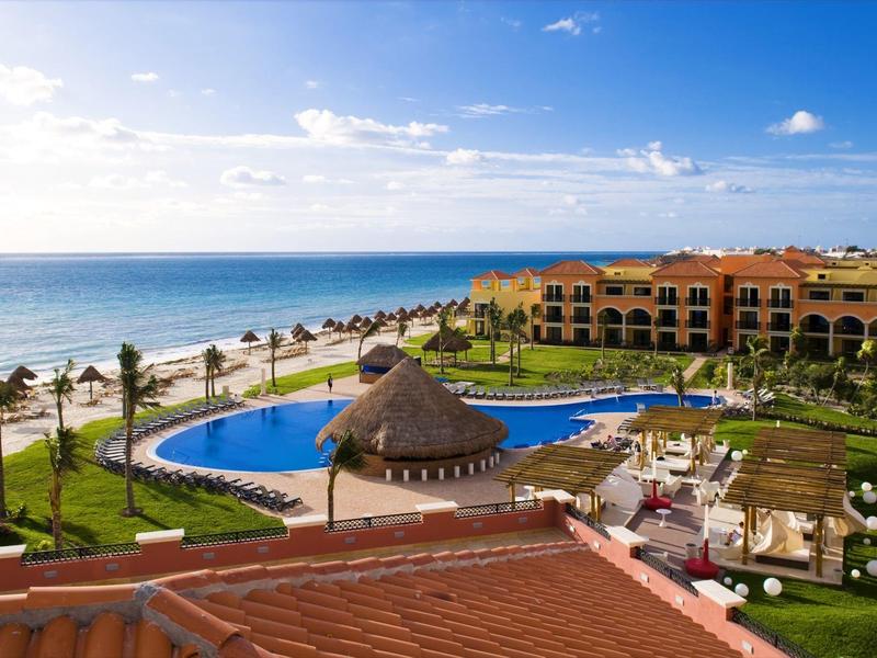 Resort con piscina, palme e vista oceano sotto un cielo azzurro.