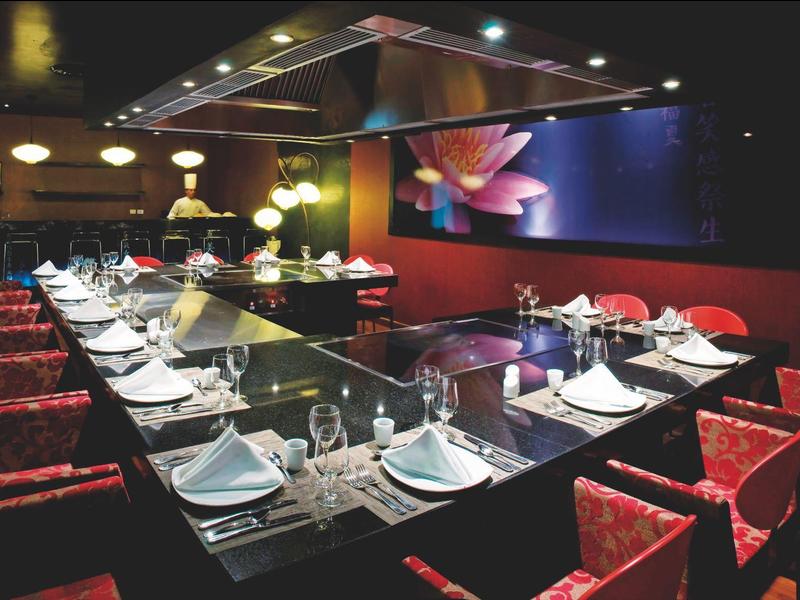 Ristorante moderno con sedie rosse, tavolo a forma di U e grande dipinto murale.