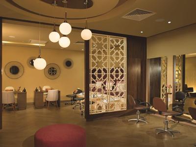 Eleganter Friseursalon mit braunen Stühlen, runden Lampen und dekorativen Raumteilern.