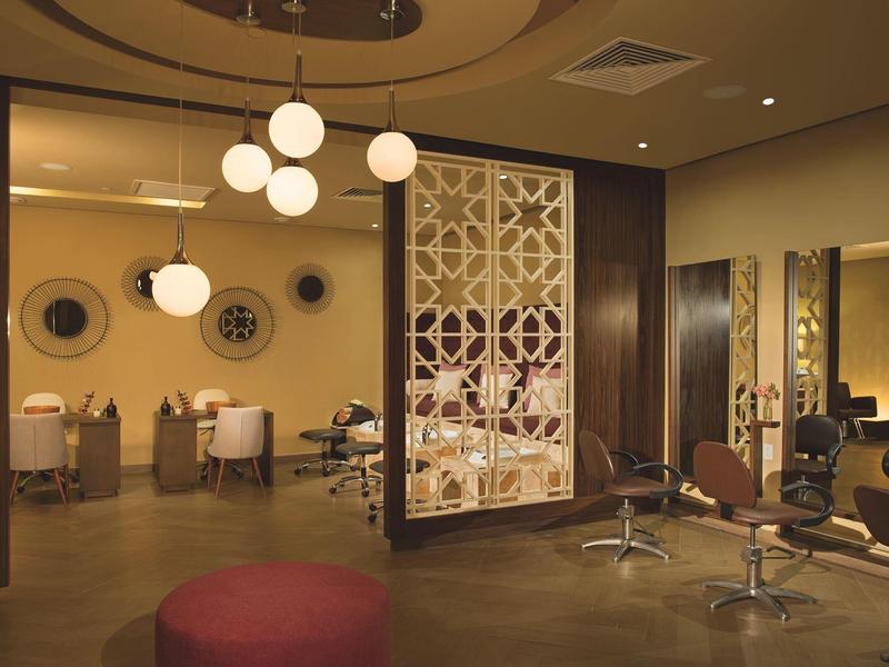 Salone moderno dell'hotel con sedie eleganti, specchi rotondi e pareti divisorie decorative.