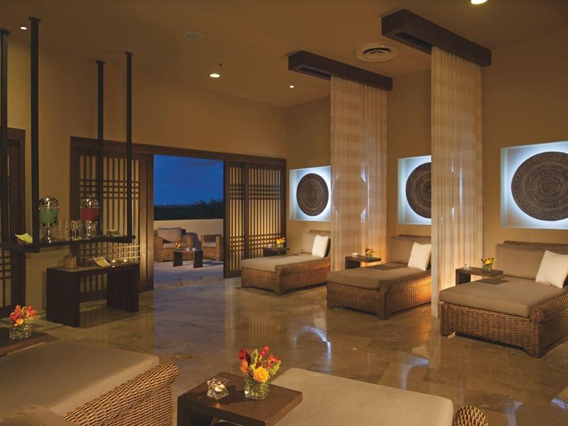 Lounge di lusso con mobili in vimini accoglienti, illuminazione soffusa e arte murale decorativa.