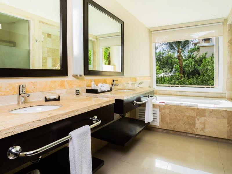 Bagno dell'hotel con doppio lavabo, grande specchio, asciugamani e finestra con vista sul verde.