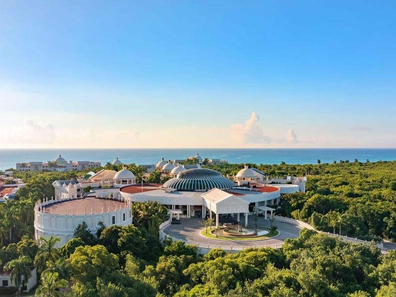 Complesso alberghiero con edifici rotondi circondati dal verde e vista mare sotto un cielo terso.
