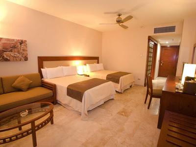 Blick durch offene Halle auf beleuchteten Poolbereich mit Springbrunnen bei Abenddämmerung.