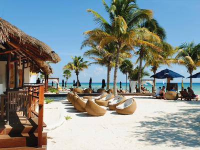 Strandresort mit Liegestühlen, Palmen und blauem Himmel am Meer.