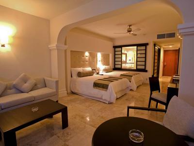 Camera d'hotel moderna con due letti, divano e zona salotto.