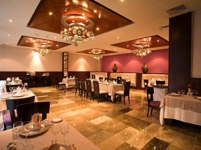 Sala da pranzo elegante con tovaglie bianche, lampadari moderni e colori caldi.