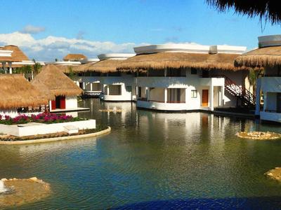 Bungalow con tetti di paglia intorno a uno stagno in un resort tropicale.