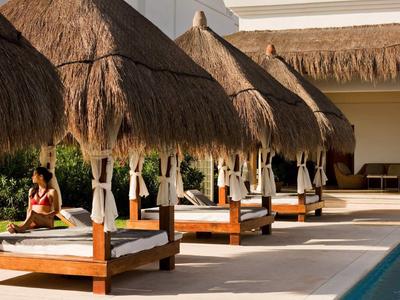 Lettini all'aperto con tetti di paglia accanto a una piscina in un resort.