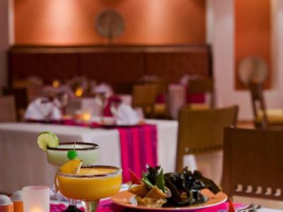 Ristorante moderno con tavolo apparecchiato, cocktail e piatti su una tovaglietta rossa.