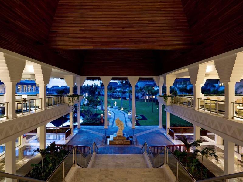 Vista di un'area piscina di un hotel moderno con fontane illuminate e aree coperte di seduta di notte.