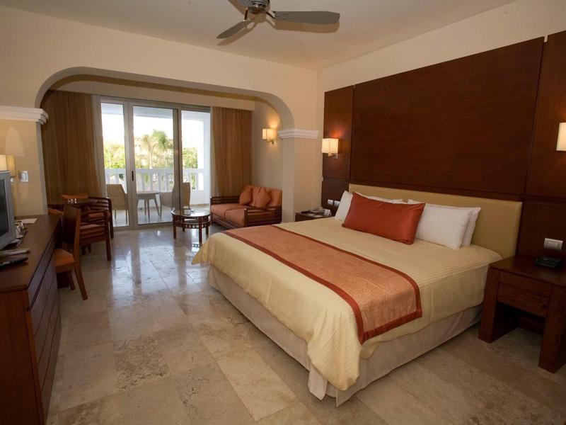 Camera d'albergo moderna con letto grande, divano e balcone con vista esterna.