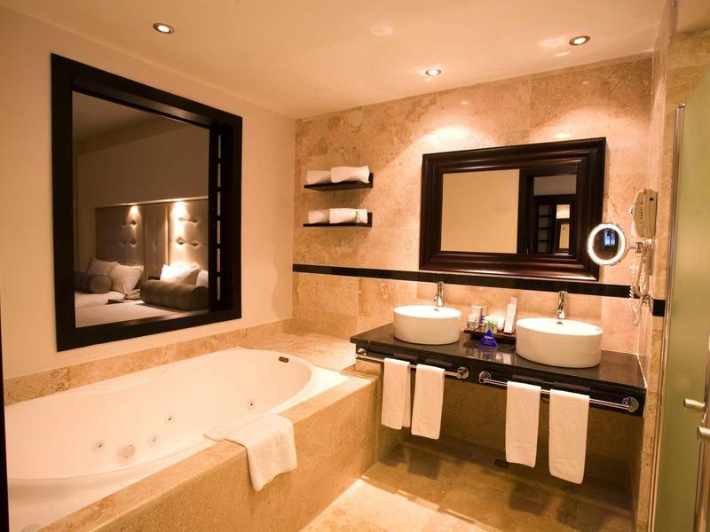 Bagno d'hotel moderno con vasca, doccia, lavabo e grande specchio.