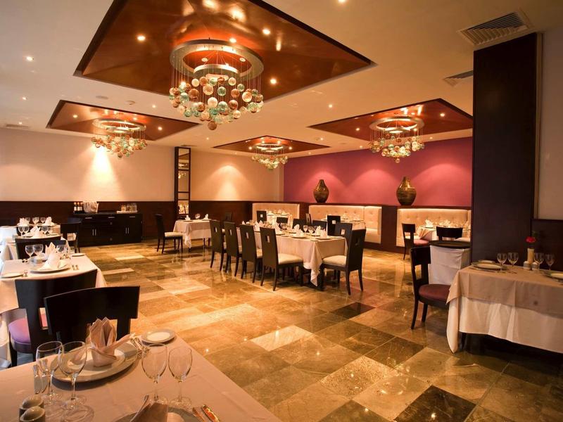 Sala da pranzo elegante con tovaglie bianche, lampadari moderni e colori caldi.