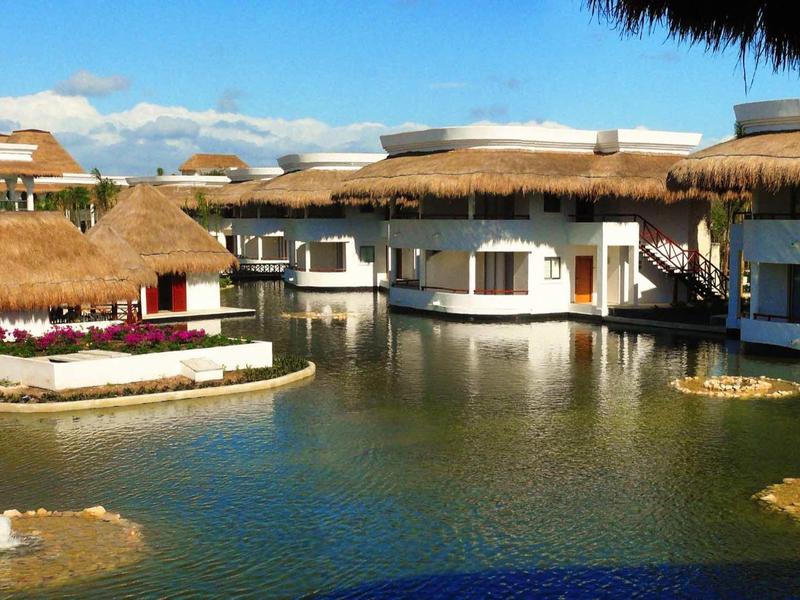 Bungalow con tetti di paglia intorno a uno stagno in un resort tropicale.