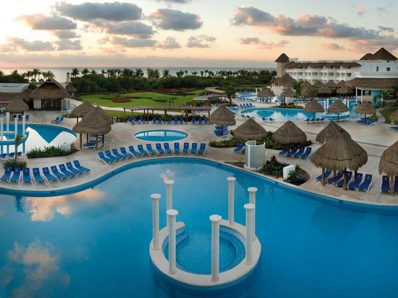 Grande piscina dell'hotel con bar circolari e lettini al tramonto