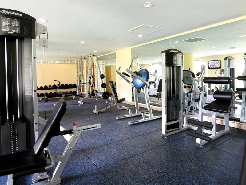 Palestra luminosa dell'hotel con attrezzi e grandi specchi.