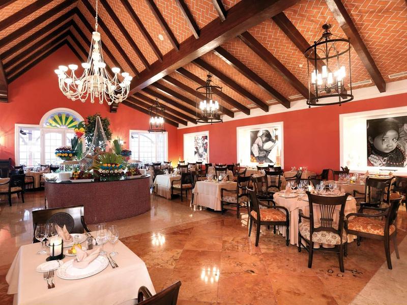 Ristorante elegante con soffitti alti in legno, lampadari e pareti rosse.