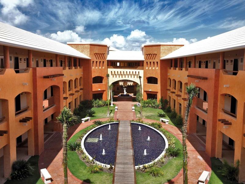 Cortile di un hotel con una fontana circolare e più piani sotto un cielo blu.