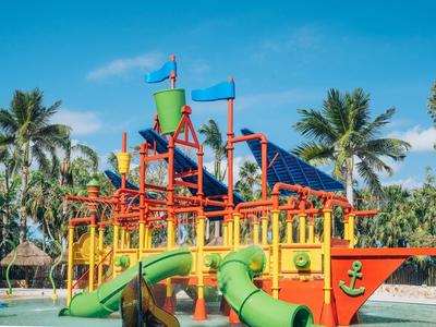 Parco giochi acquatico colorato con scivoli e palme sotto un cielo azzurro.