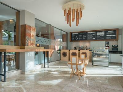 Bar luminoso con mobili in legno, grandi finestre e illuminazione moderna.