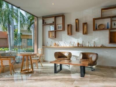 Lobby di hotel moderna con divano in pelle, sedie in legno e grandi finestre con vista sulle palme.