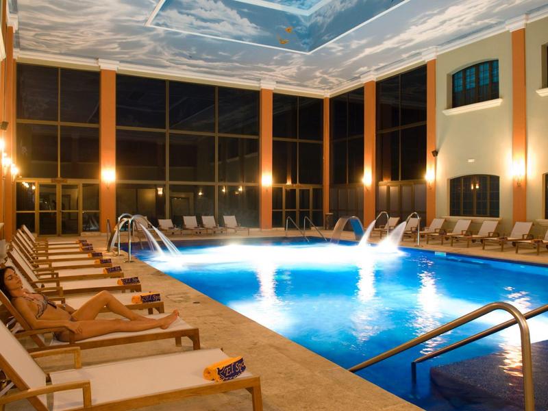 Piscina coperta con lettini e illuminazione d'atmosfera di notte.