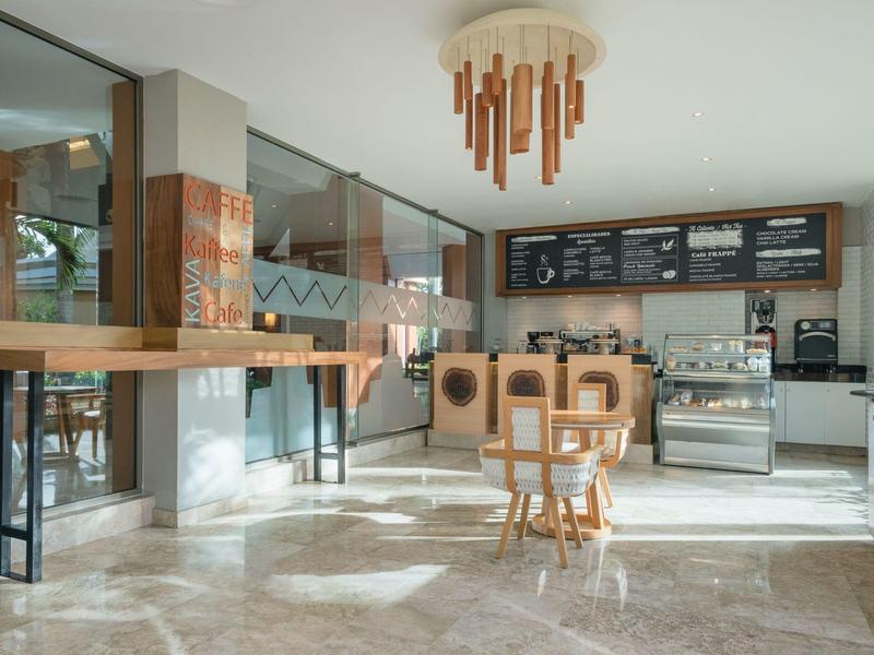 Bar luminoso con mobili in legno, grandi finestre e illuminazione moderna.