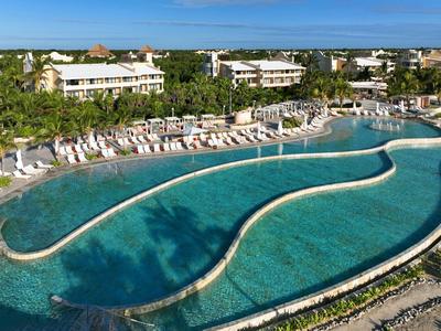 Grande piscina all'aperto in un complesso alberghiero sotto un cielo azzurro.