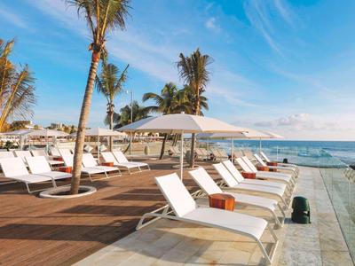 Lettini bianchi vicino alla piscina con vista sull'oceano e cielo sereno.