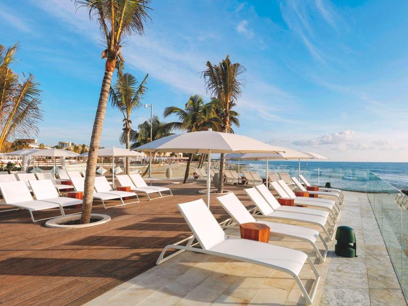 Lettini bianchi vicino alla piscina con vista sull'oceano e cielo sereno.