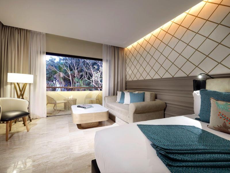 Camera d'hotel moderna con letto grande, poltrona e terrazza con vista sul giardino.