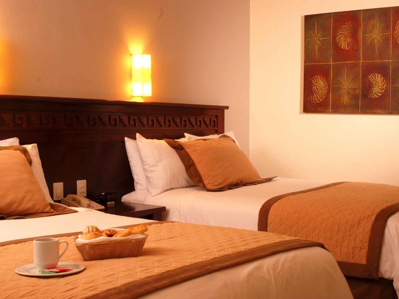 Camera d'hotel accogliente con due letti singoli, toni caldi e colazione pronta.