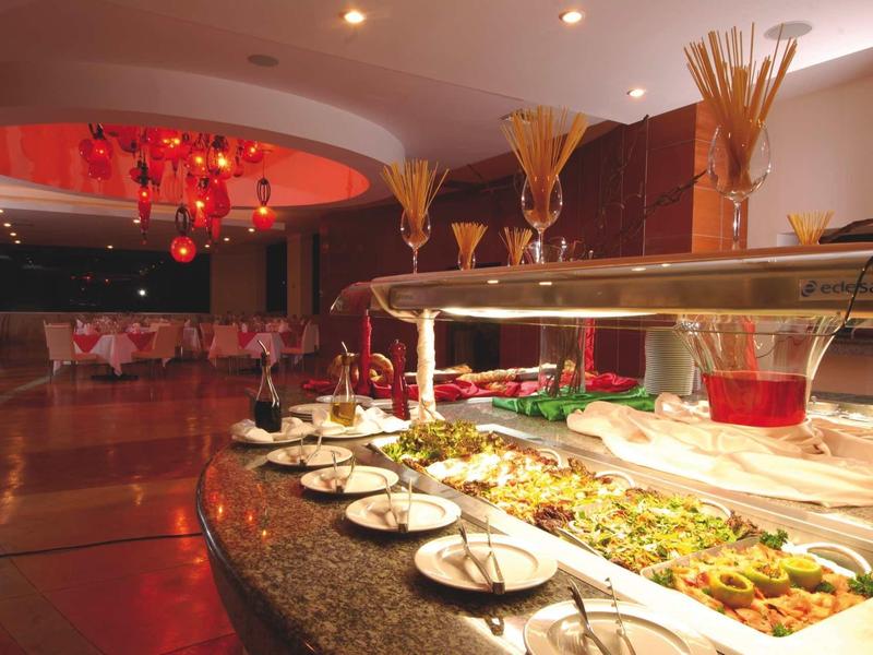 Buffet con vari piatti sotto copertura di vetro in un ristorante moderno.