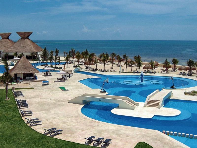 Grande piscina con lettini e vista sulla spiaggia e sul mare.