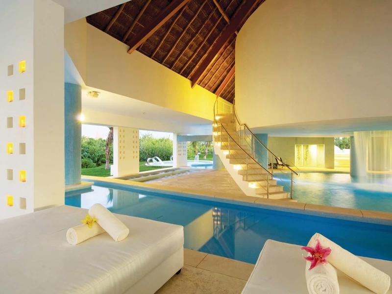 Area piscina interna lussuosa con scala a chiocciola e zone relax.