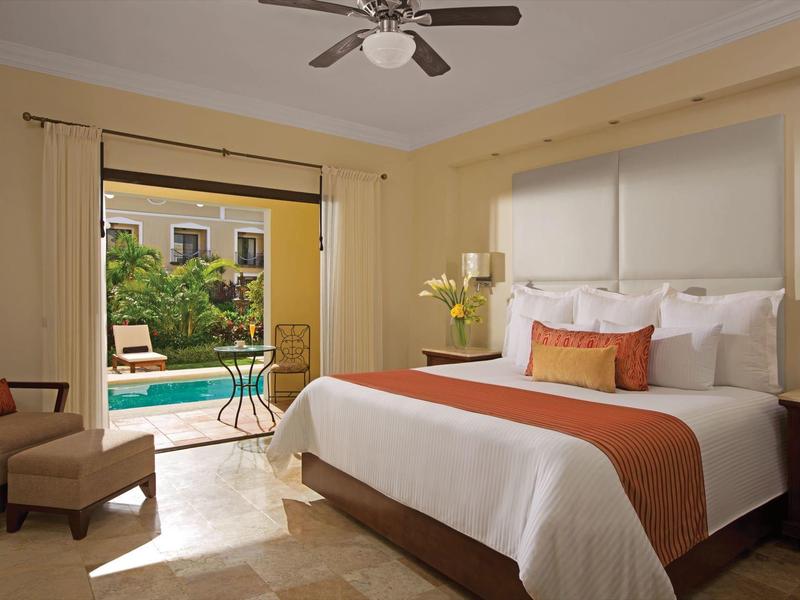 Camera d'hotel con letto king, poltrona e porta patio che si apre alla piscina esterna.