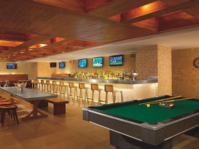 Moderne Hotelbar mit Billardtisch und Sitzgelegenheiten in warmem Ambiente.