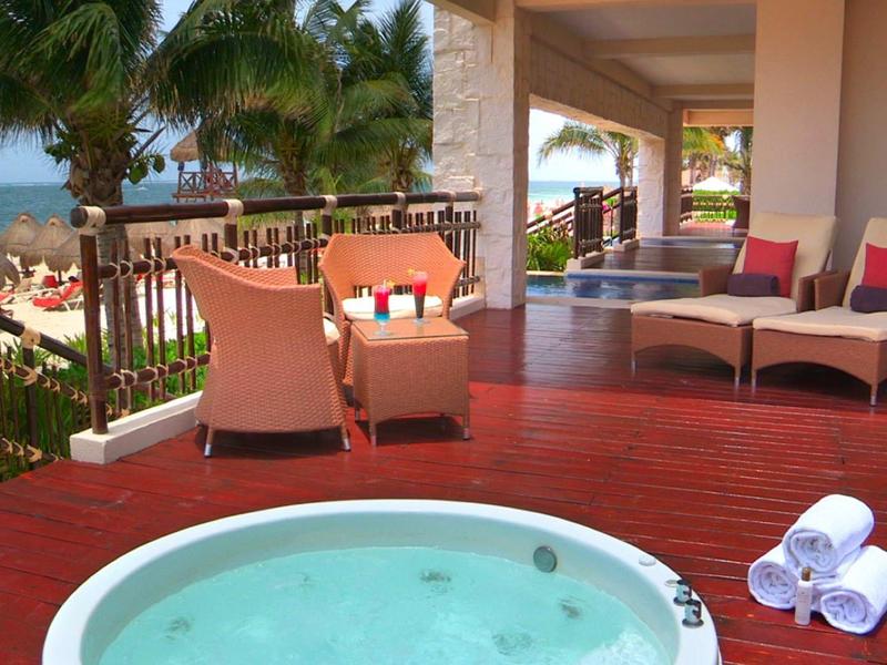 Terasa s vířivkou, dvěma křesly a výhledem na moře v hotelovém resortu.