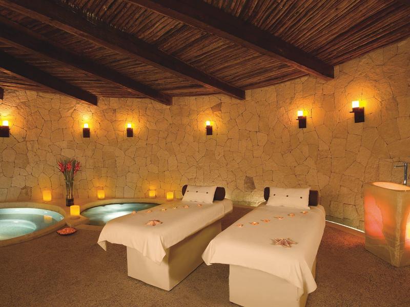 Accogliente spa con due lettini da massaggio, vasche e illuminazione soffusa.