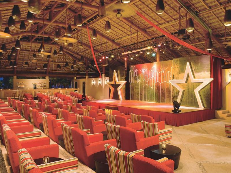 Sala conferenze con poltrone a righe e un palco con stelle illuminate.