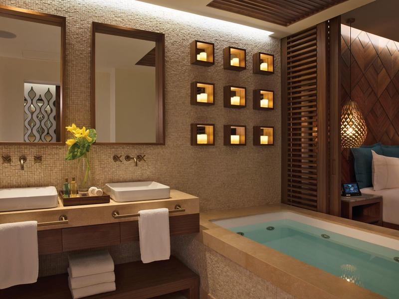 Camera d'hotel elegante con due lavandini, vasca da bagno e letto accogliente sullo sfondo.