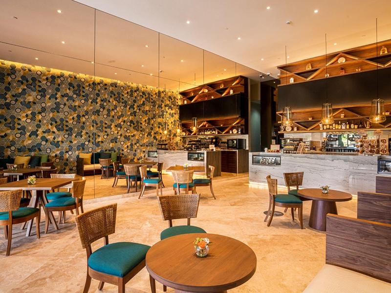 Caffetteria moderna con dettagli in legno e marmo, illuminazione calda e posti a sedere confortevoli.