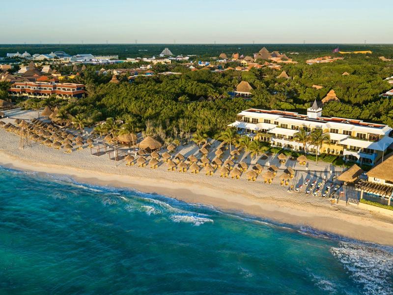 Spiaggia con ombrelloni e edifici dell'hotel lungo la costa sotto un cielo limpido.