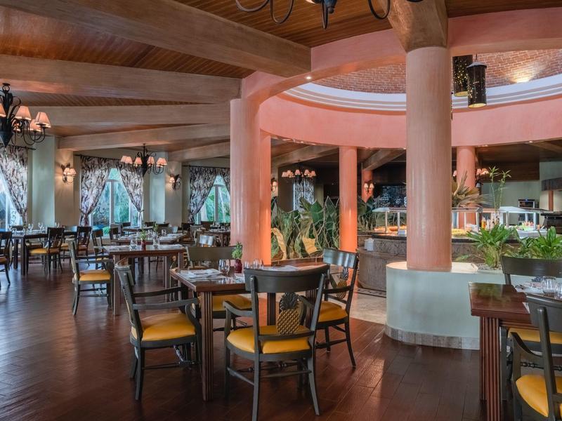 Ristorante elegante con pavimento in legno, tavoli apparecchiati e grandi finestre con tende.