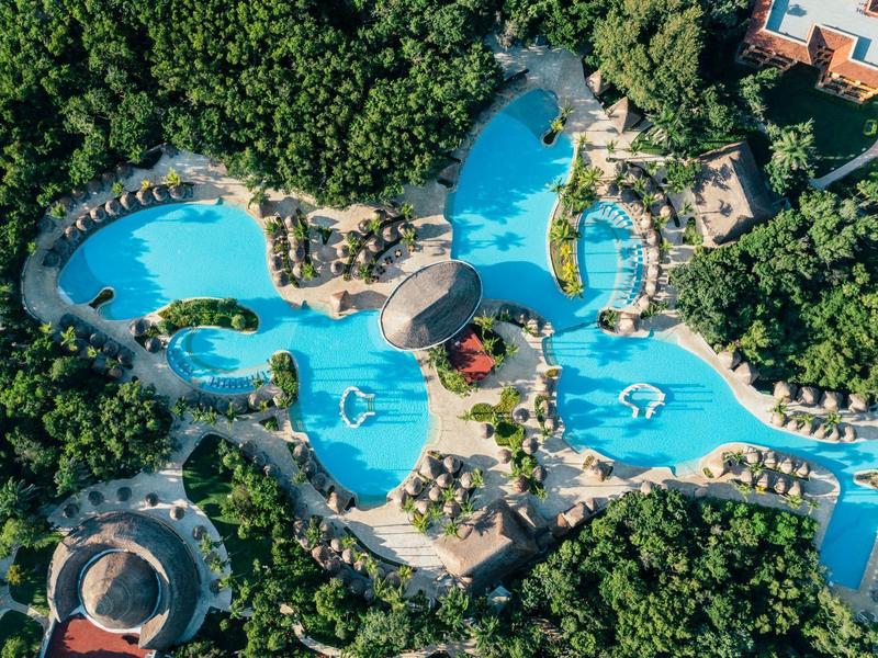 Vista aerea di una grande piscina dell'hotel con varie sezioni circondate da alberi.