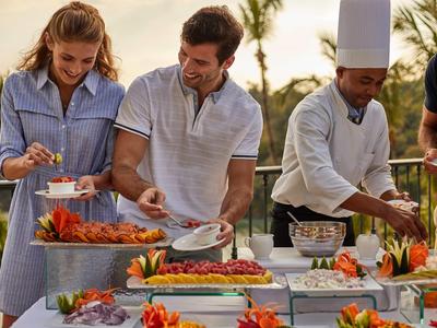 Persone che godono di un buffet all'aperto con una varietà di cibi e frutta decorativa.