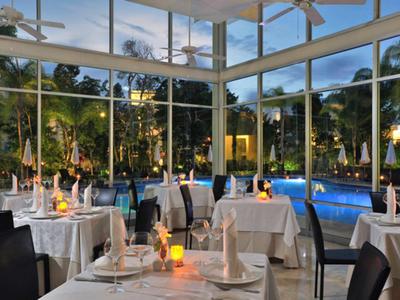 Elegantes Restaurant mit weißen Tischdecken und Blick auf einen beleuchteten Pool bei Dämmerung.